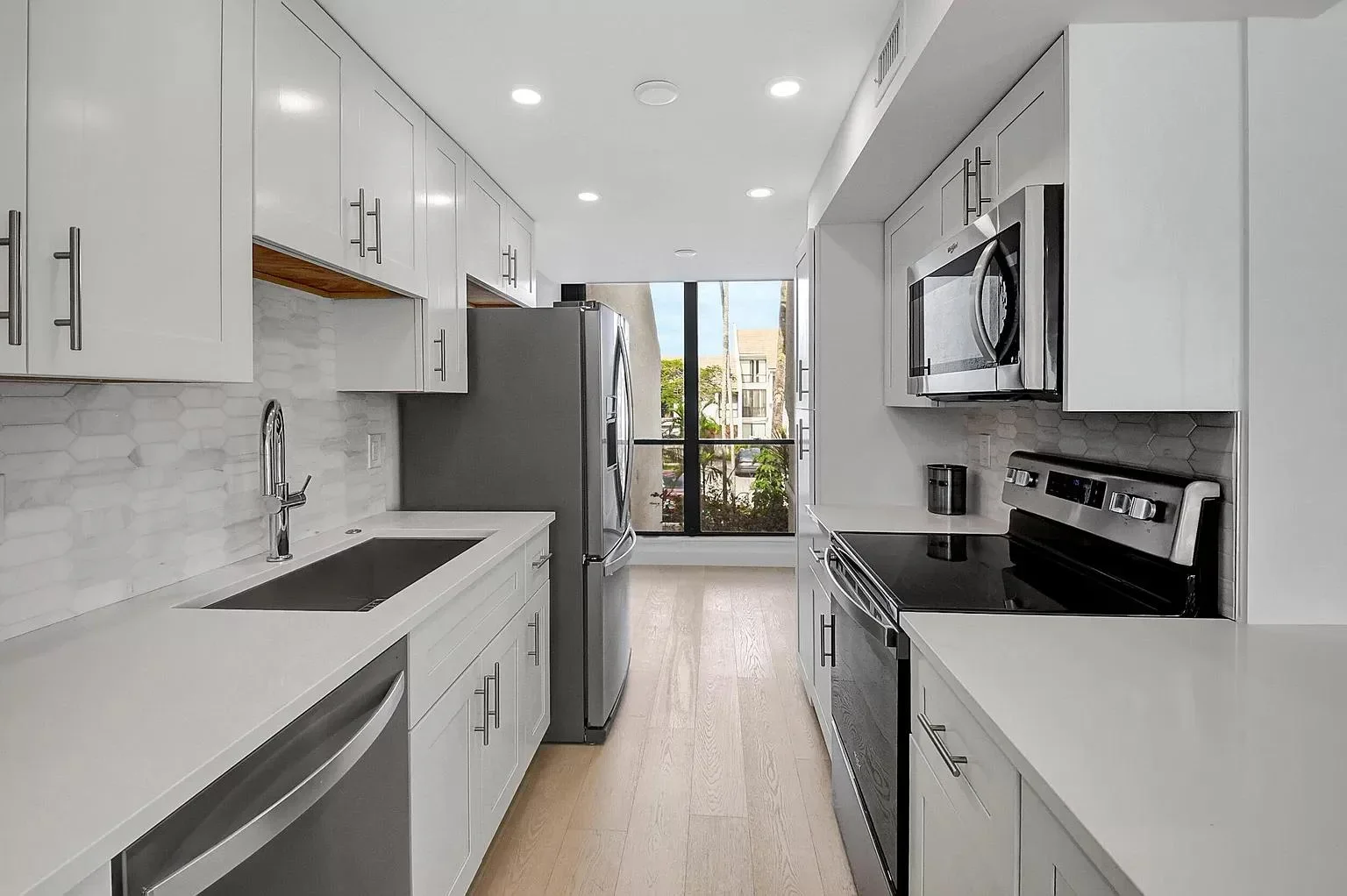 White kitchen cabinets, marble backsplash, quartz counters, stainless steel appliances, recessed lighting