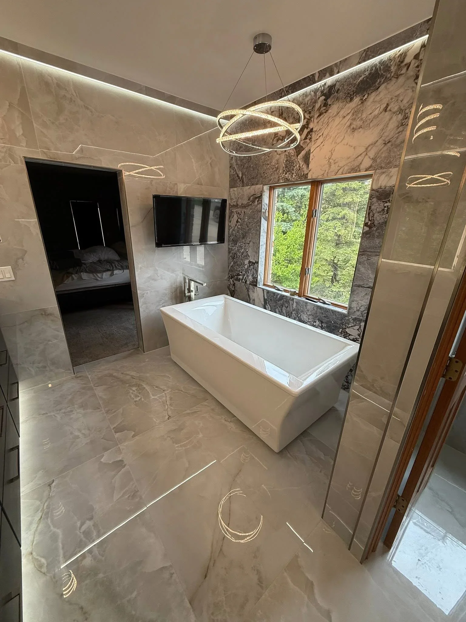 Marble bathroom with freestanding tub, LED lighting, and polished stone finishes