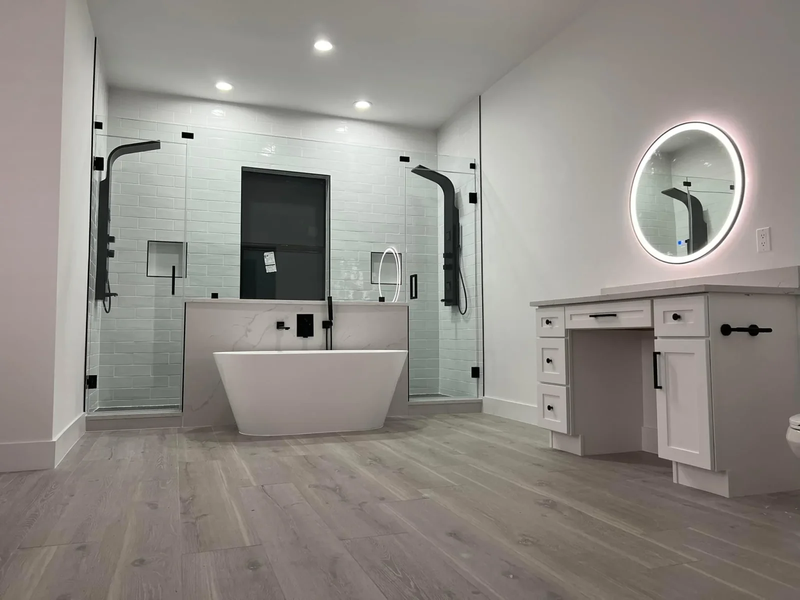 Modern bathroom with white subway tile, freestanding tub, frameless glass shower, and marble vanity