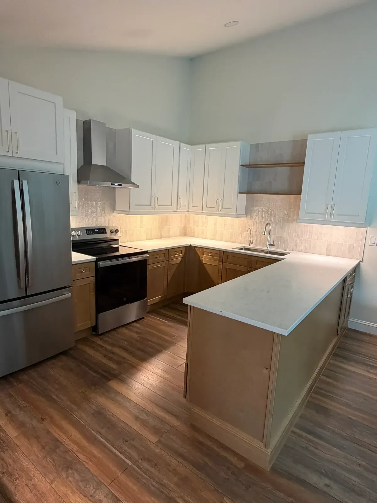 Kitchen with white upper cabinets, wood lower cabinets, island, and stainless steel appliances