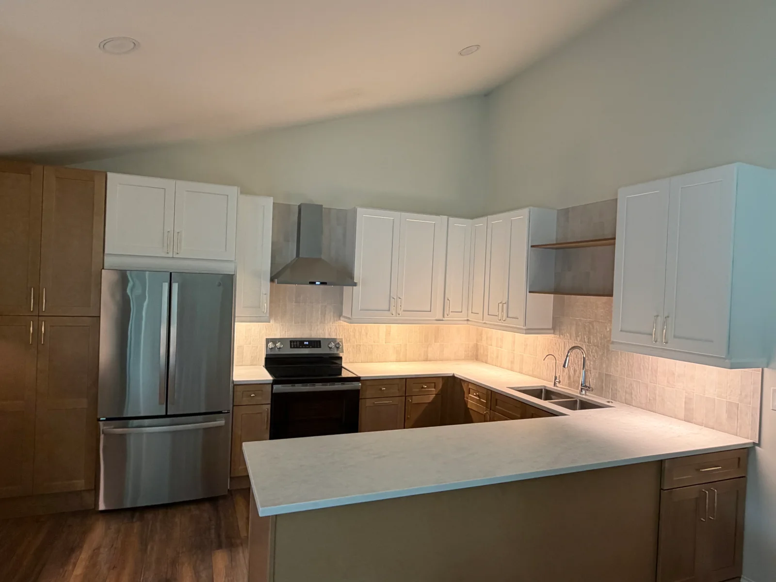 Kitchen with white and wood cabinetry, stainless steel appliances, quartz island, subway tile backsplash