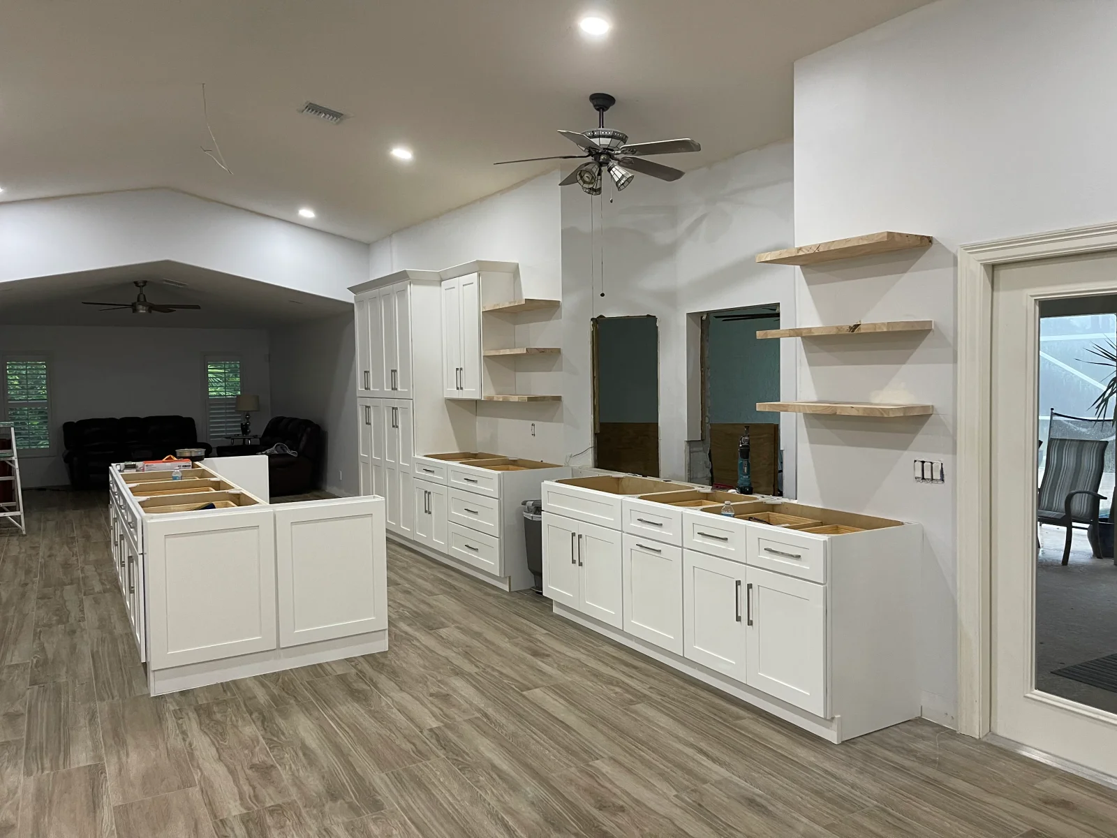 White cabinetry kitchen with island, open shelving, and vinyl plank flooring