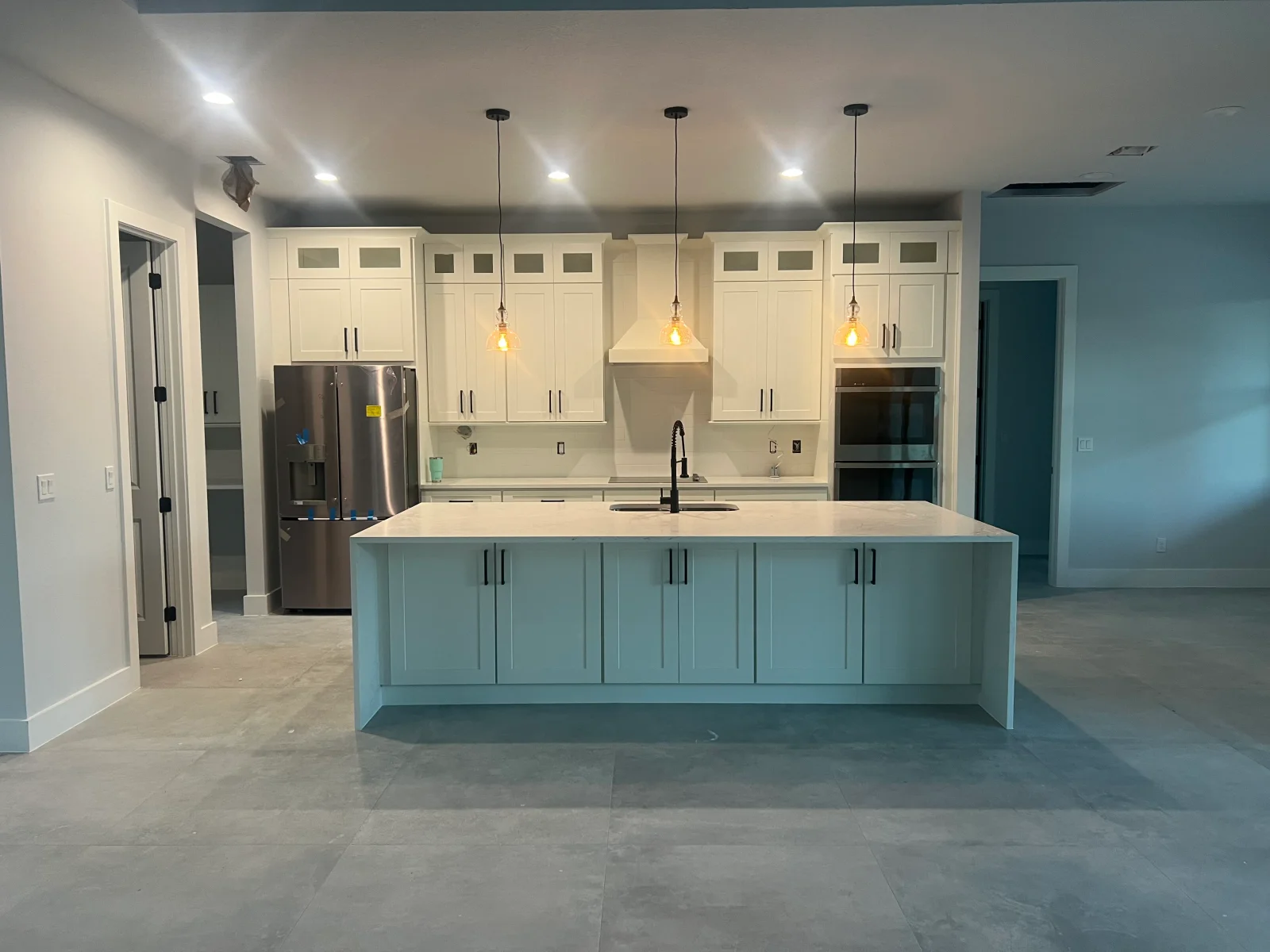 Two-tone kitchen with cream upper cabinets, turquoise island, white quartz counters, and stainless steel appliances