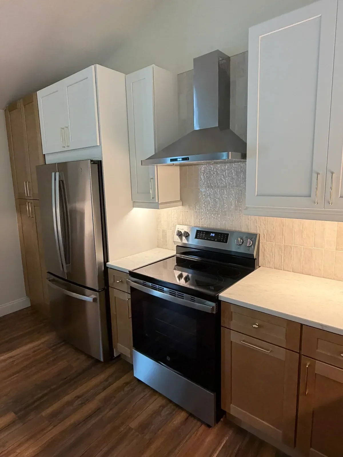 White upper and dark wood lower cabinets with stainless steel appliances and gray tile backsplash
