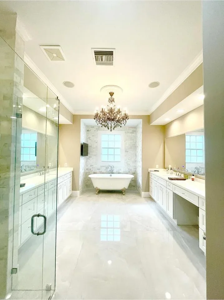 Master bathroom with marble flooring, dual vanities, freestanding tub, and glass shower enclosure