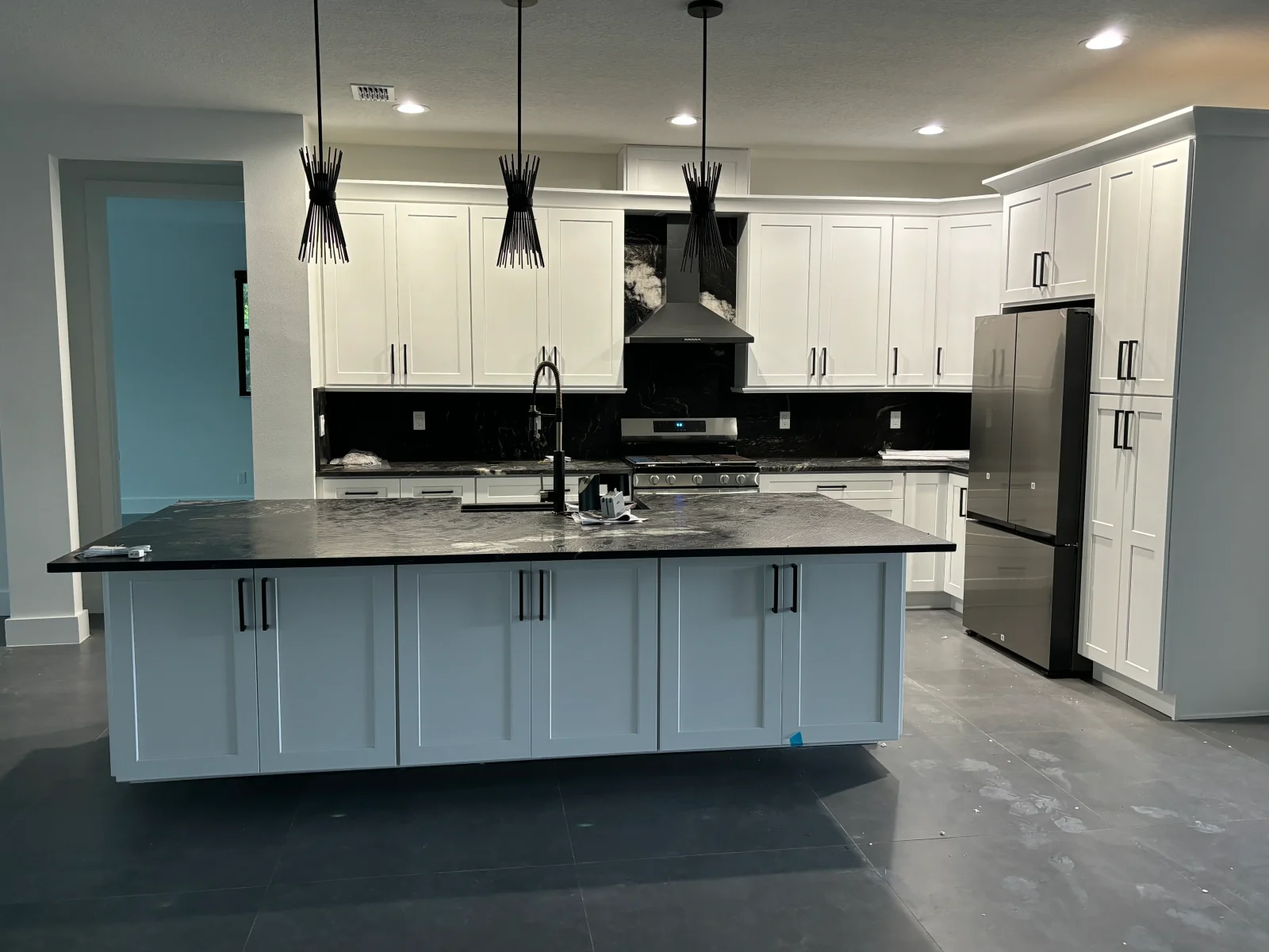 White and blue kitchen cabinets with black granite countertops and stainless steel appliances