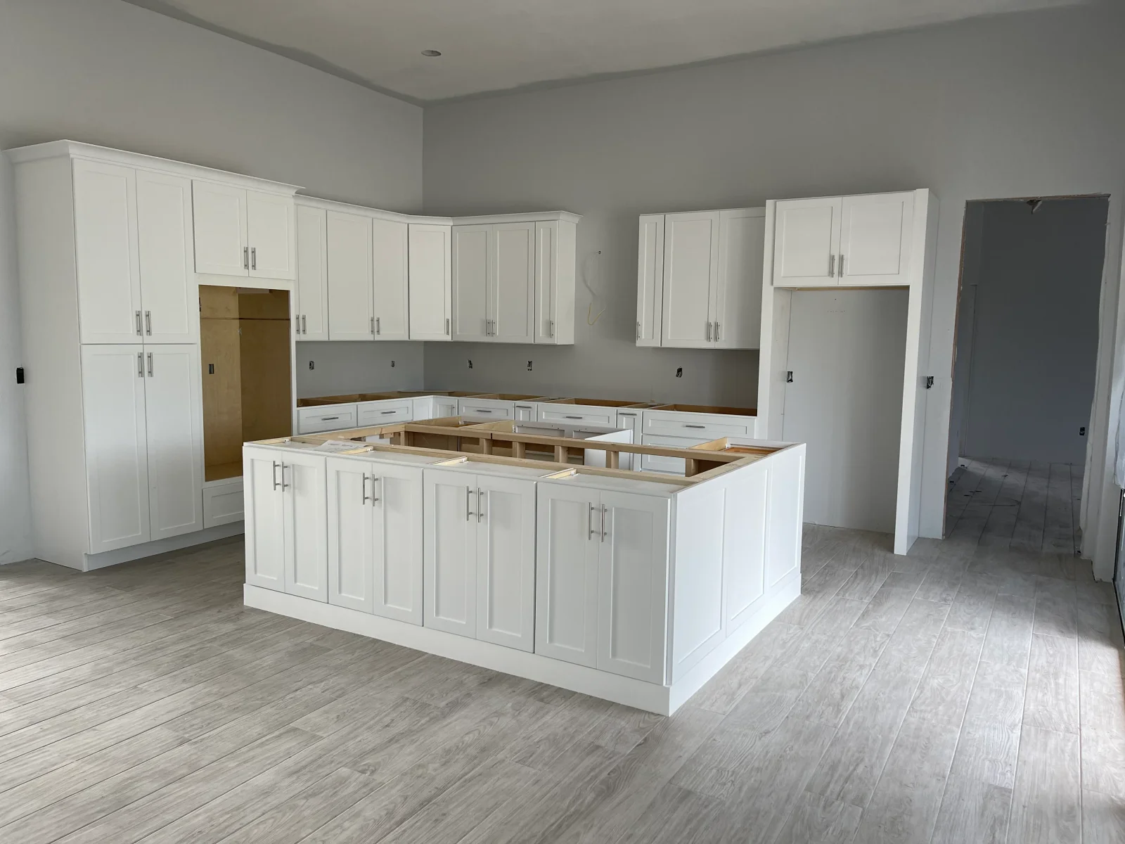 White shaker kitchen cabinets with wood island countertop and stainless hardware