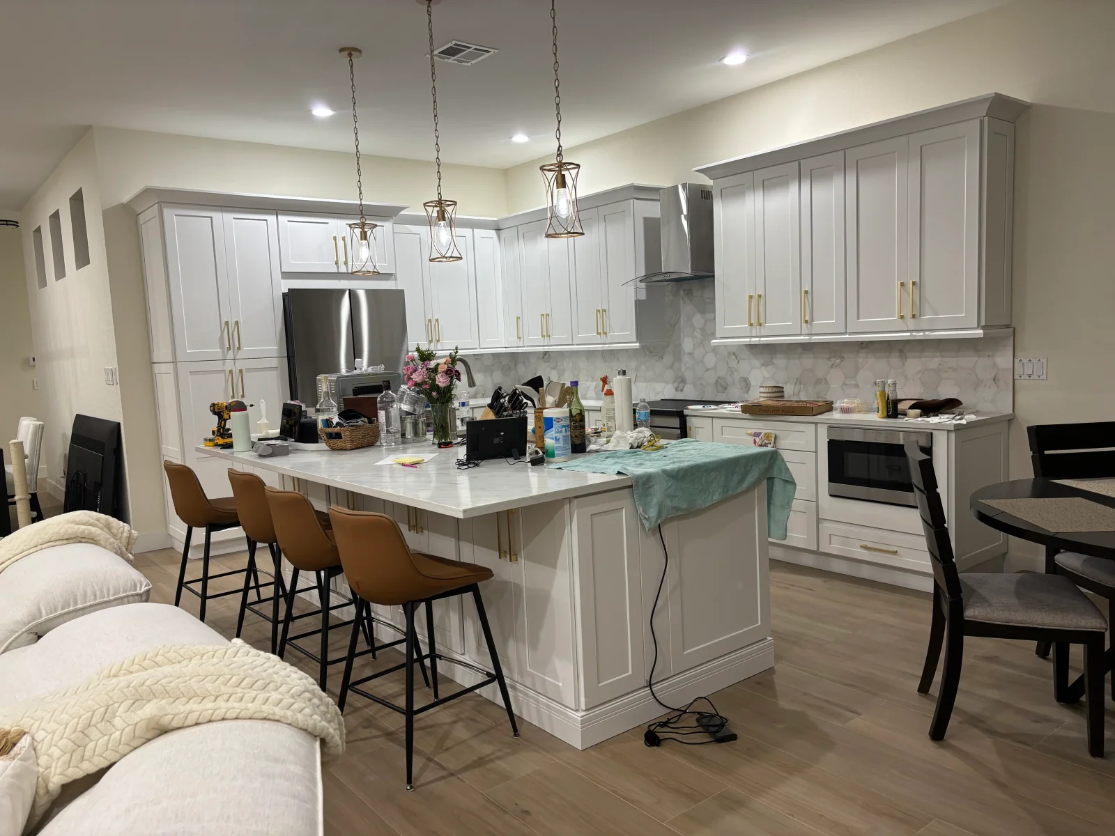 White shaker cabinets, quartz island countertop, marble backsplash, stainless steel appliances, pendant lights