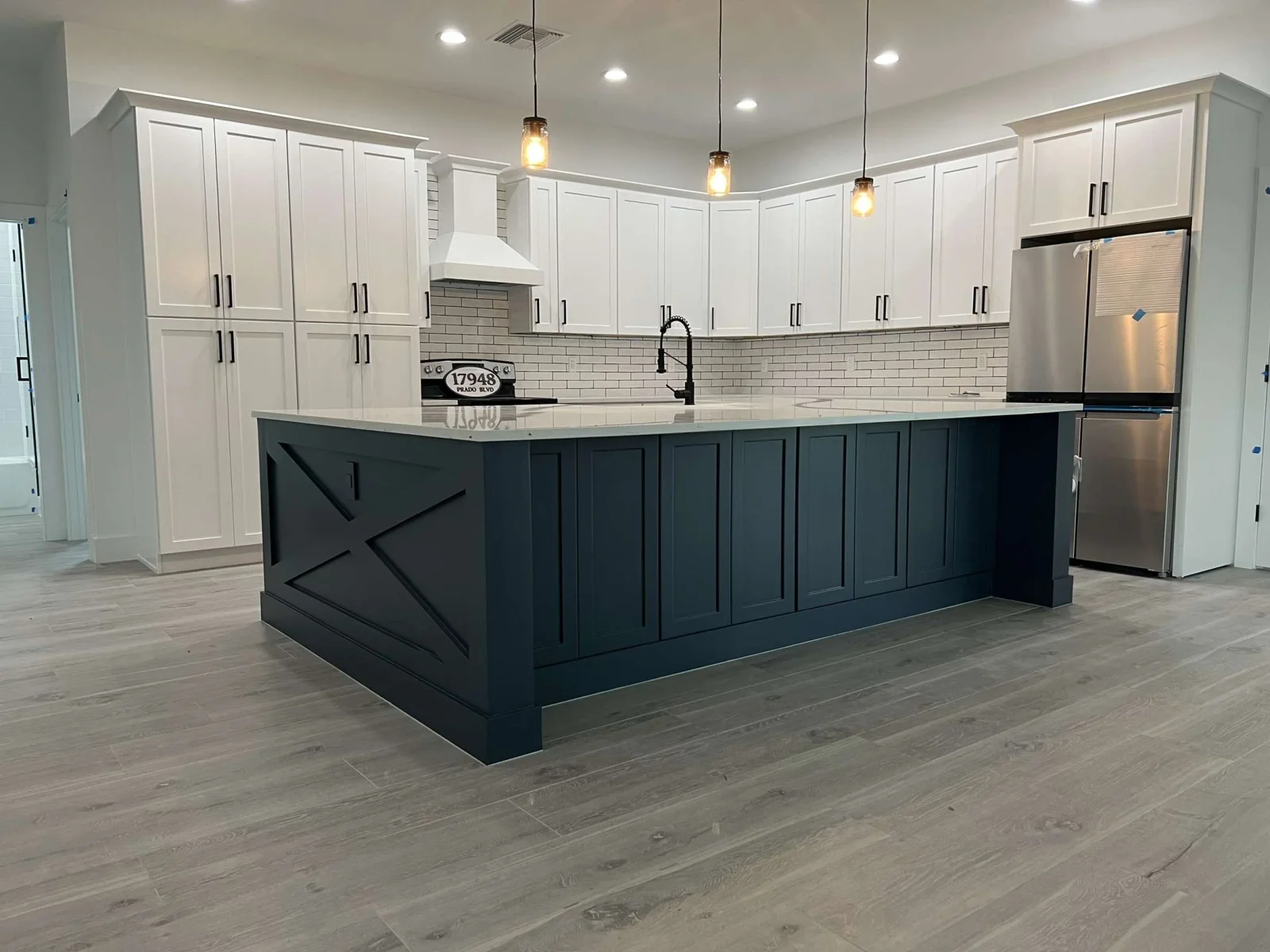 White and dark blue kitchen with shaker cabinets, subway tile, and quartz countertops