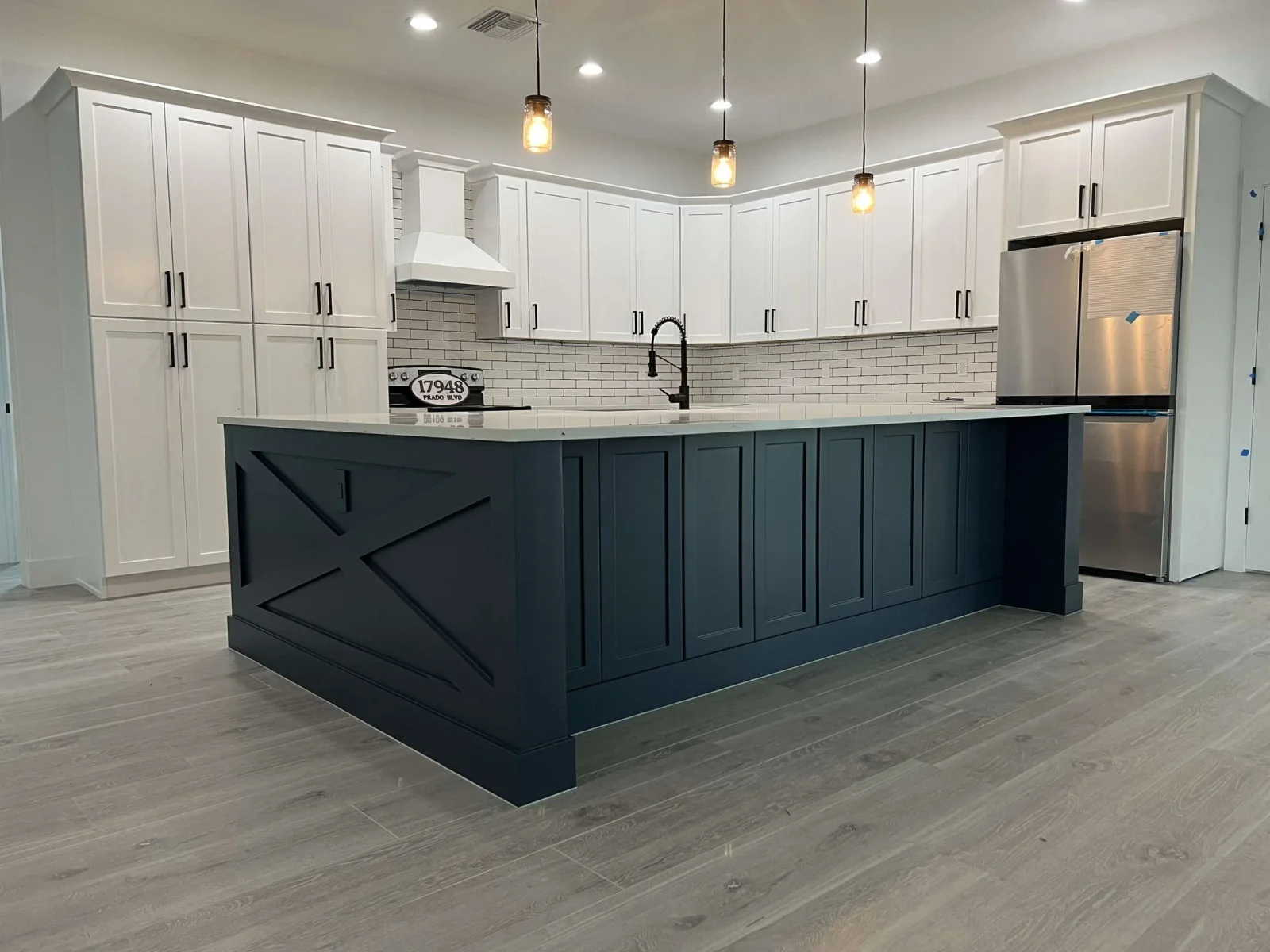 White and navy kitchen with shaker cabinets, subway tile backsplash, quartz counters, and pendant lights