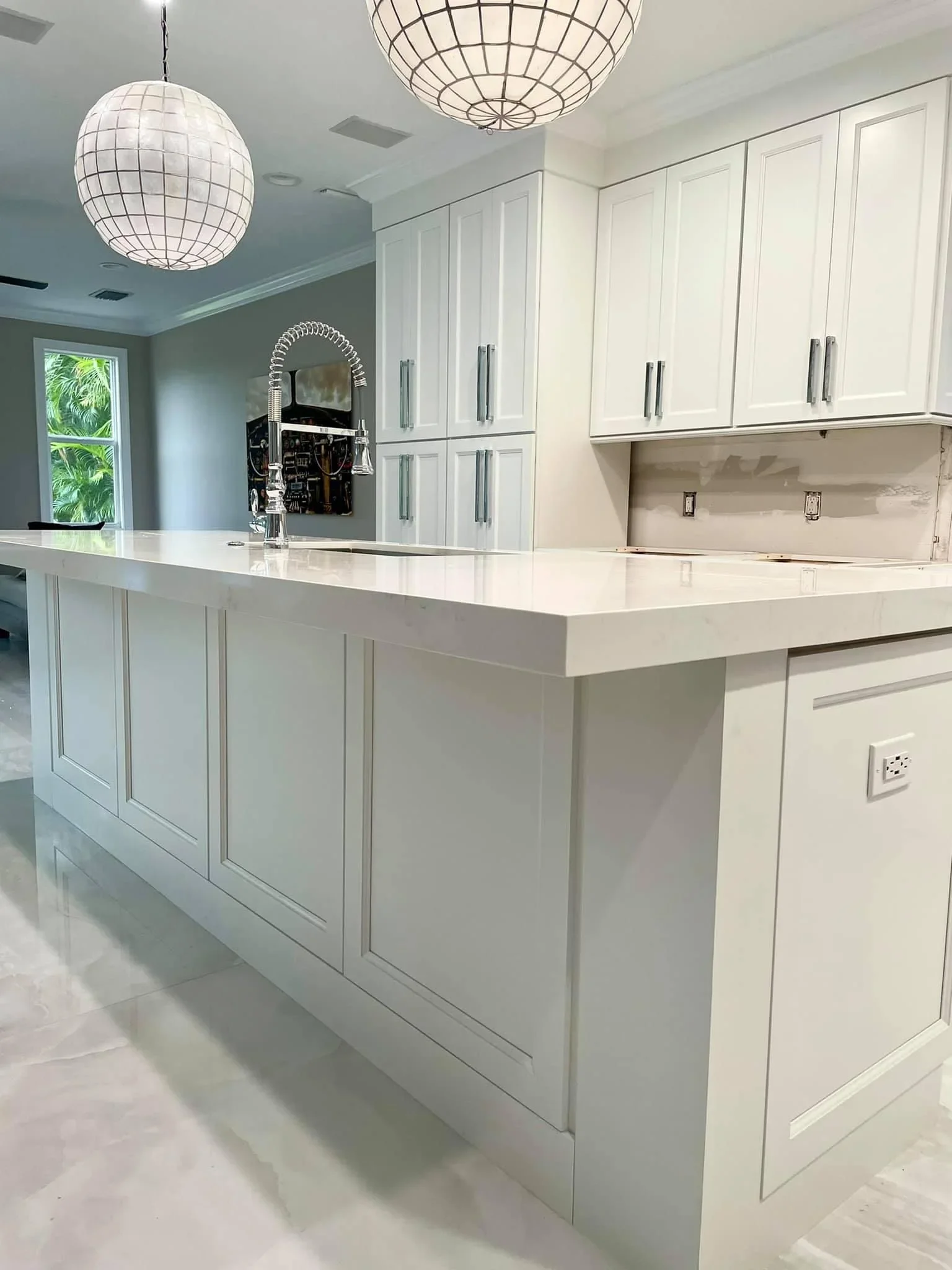 White shaker cabinets, quartz waterfall island, chrome faucet, globe pendants, gray accent wall