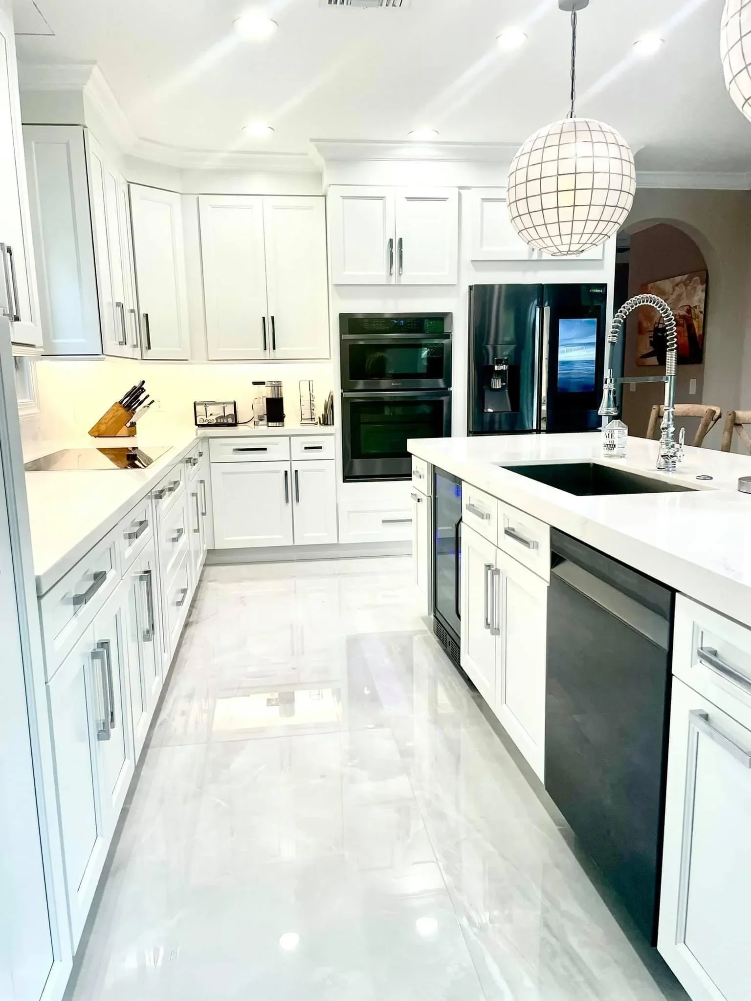 White kitchen with island, quartz counters, black appliances, and pendant lighting