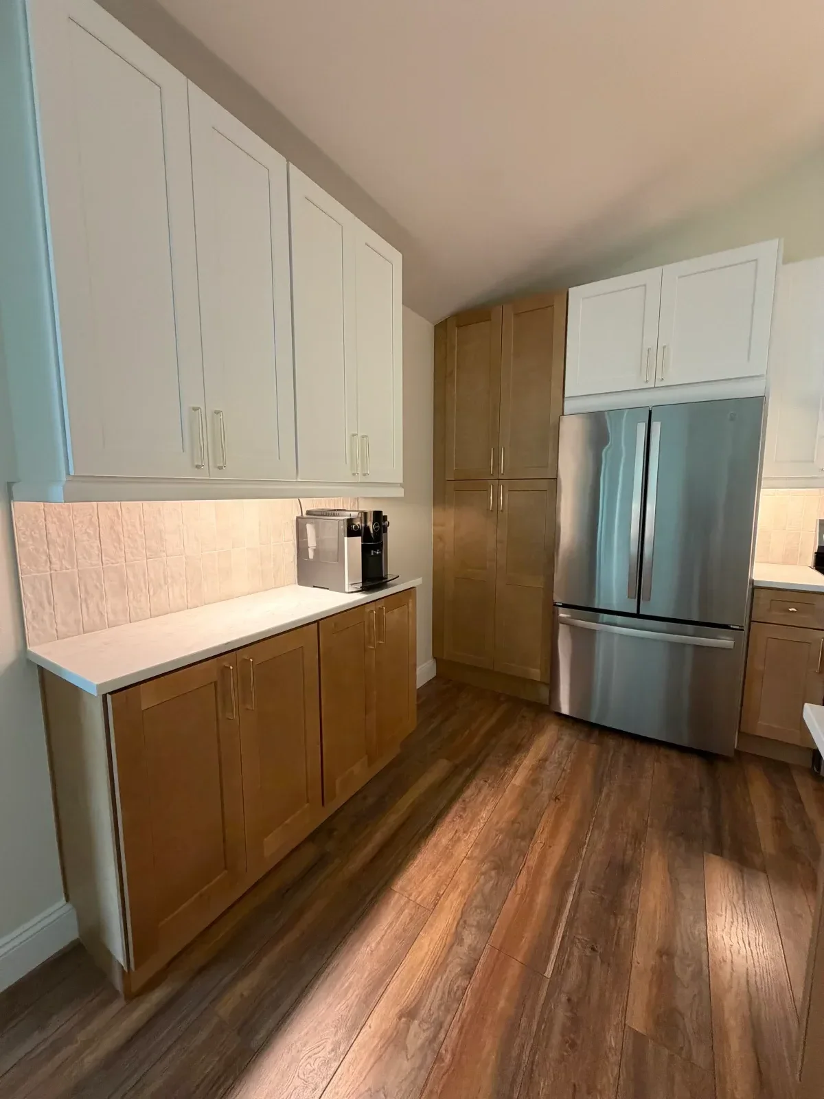 Kitchen with white and wood cabinetry, stainless steel appliances, and mixed flooring materials
