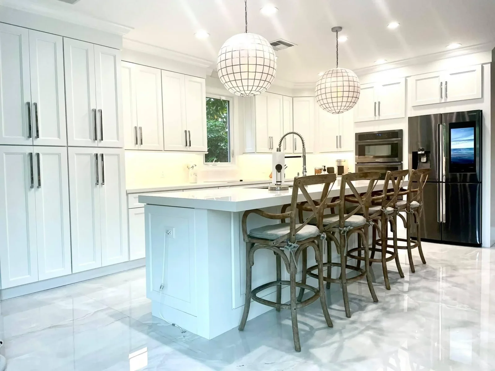 White cabinetry kitchen with blue island, quartz counters, stainless appliances, and pendant lights