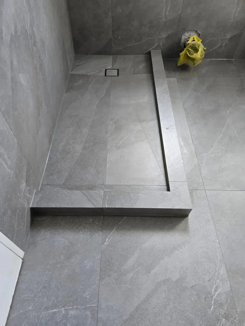 Gray marble tile shower base with linear drain and matching wall tile installation