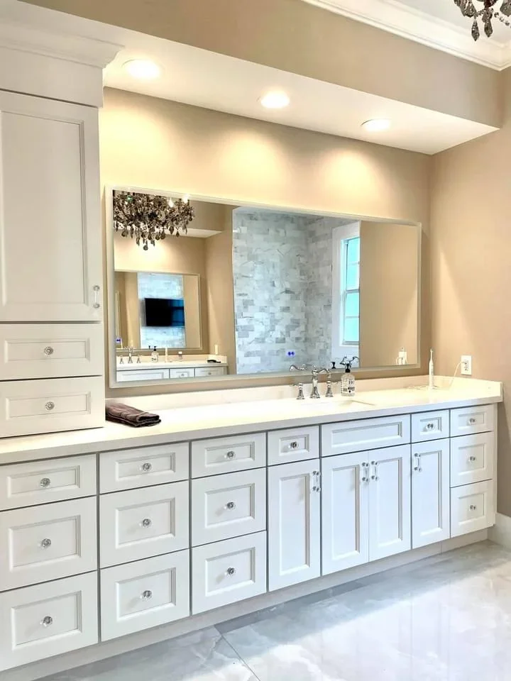 White bathroom vanity with quartz countertop, dual sinks, and large illuminated mirror
