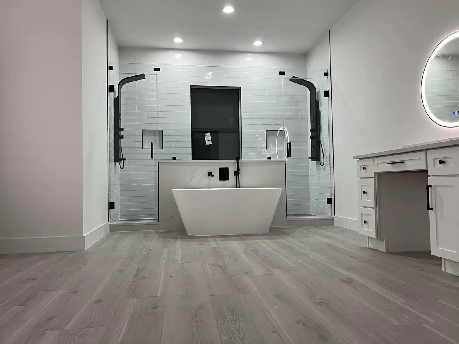Luxury bathroom with freestanding tub, dual glass shower enclosures, subway tile, and marble counters